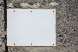 The white plastic board for posters on the stone wall.