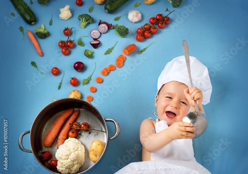 Baby boy in chef hat with cooking pan and vegetables photo