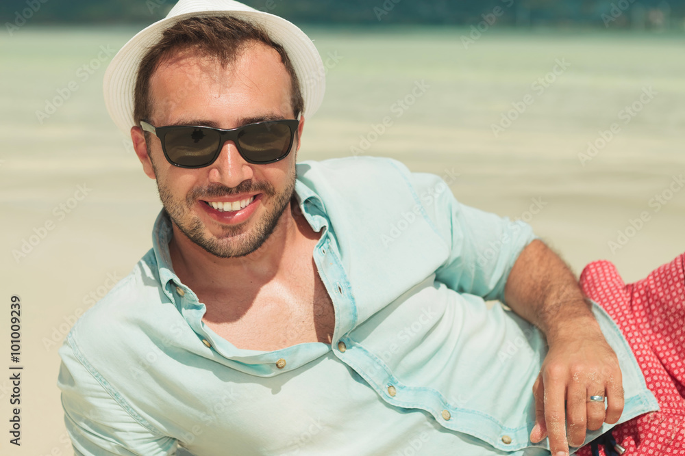smiling man wearing sunglasses and laying down the beach smiling man wearing sunglasses and laying down the beach