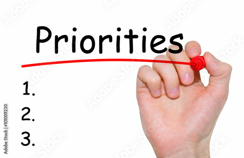 Hand writing Priorities with red marker on transparent wipe board, business concept