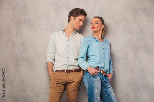 man standing with hands in pockets in studio stares at woman