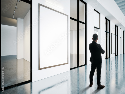 Businessman looking at blank frames in contemporary gallery. 