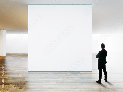 Businessman looking at blank canvas in contemporary gallery. 