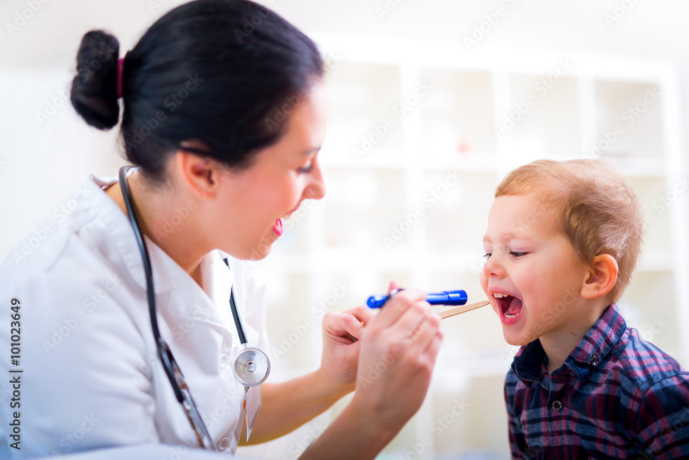 Medical doctor with child in office. Pediatrician examining little boy's throat with tongue depressor Medical doctor with child in office. Pediatrician examining little boy's throat with tongue depressor
