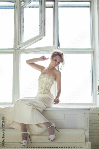 Charming beautiful young red hair girl in a white lace dress sit