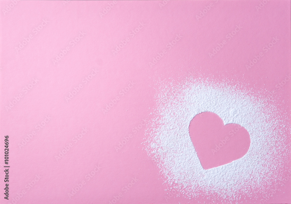 Heart shape made of icing sugar on pink grainy paper surface