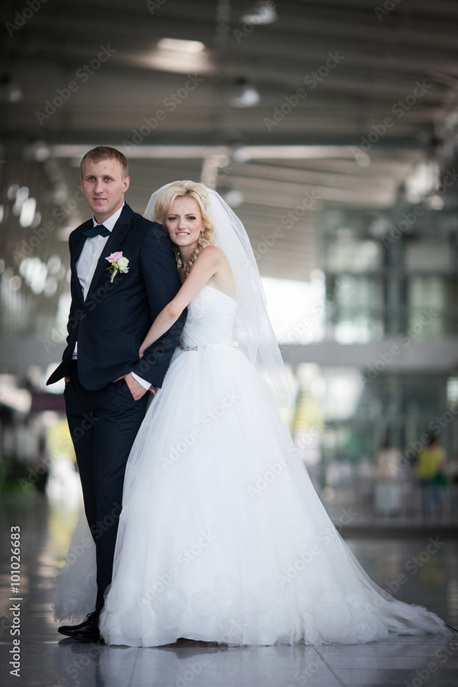 gorgeous happy blonde bride and elegant groom hugging on the bac