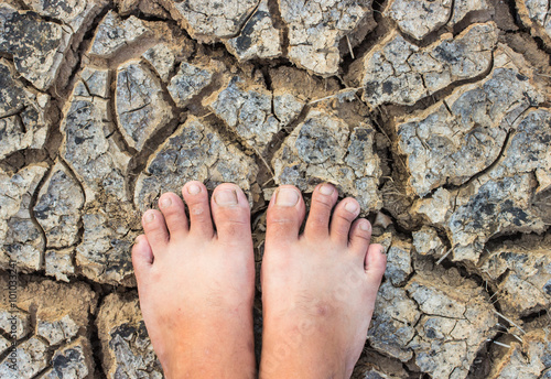 Barefoot standing on dry and cracked ground background and textu