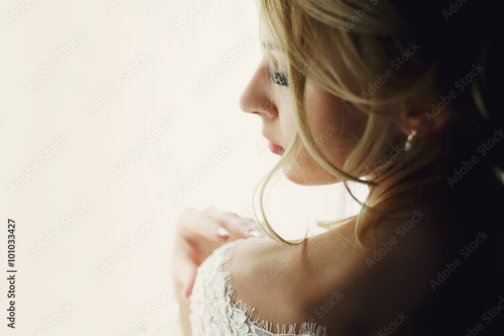 Beautiful blonde wedding bride in make-up and veil in a white dr