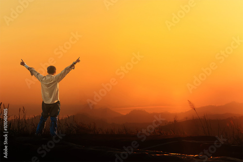 Tourist man spread hand on top of a mountain enjoying valley sun © chanwitohm