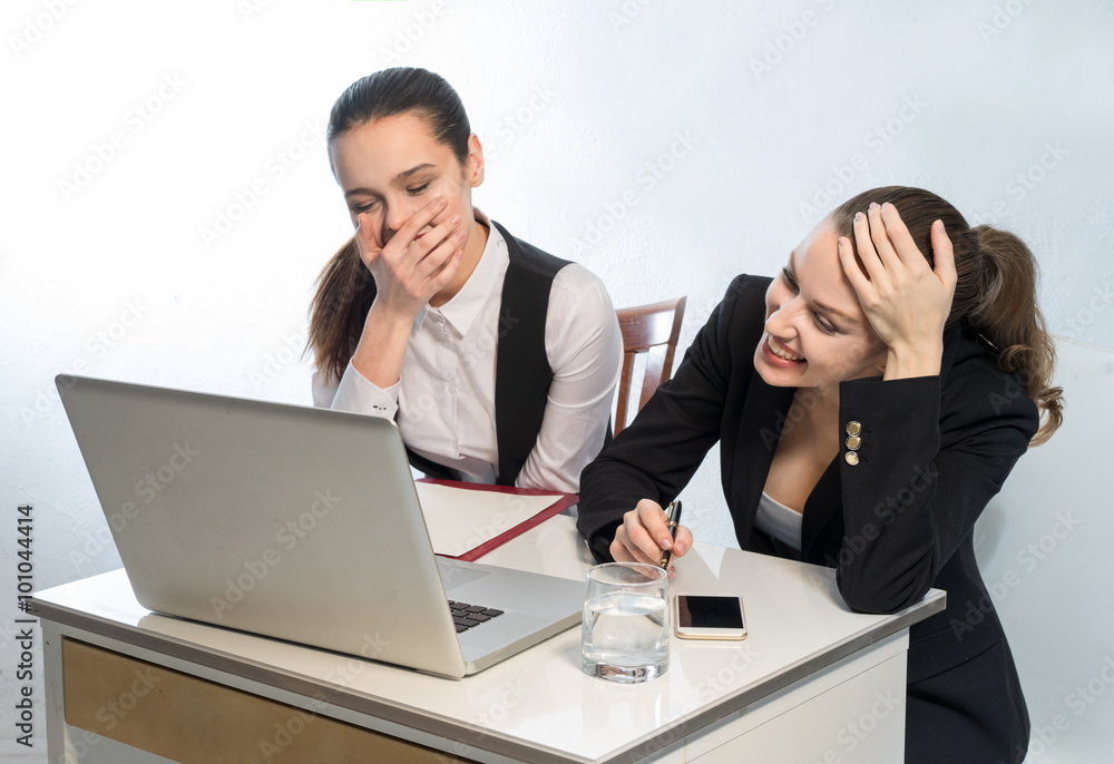 Office workers looking at laptop monitor and laugh loudly Office workers looking at laptop monitor and laugh loudly
