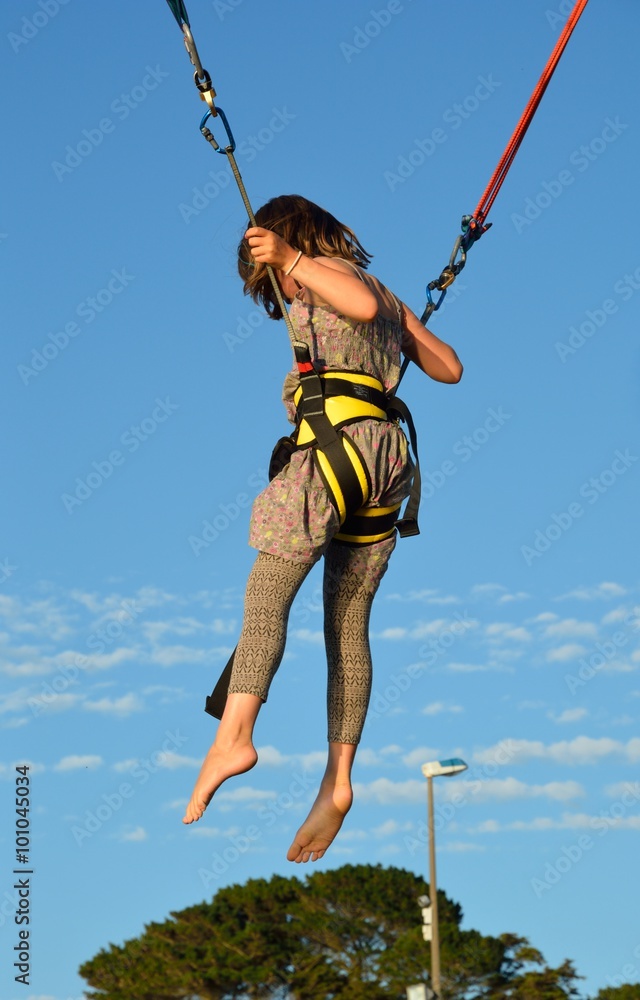 Jeune fille pratiquant le saut à l'élastique lors d'une fête foraine Photos  | Adobe Stock