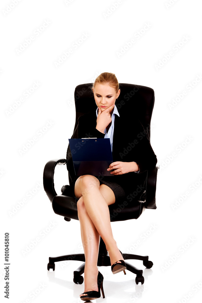 Beautiful business woman sitting on armchair and reading notes Beautiful business woman sitting on armchair and reading notes