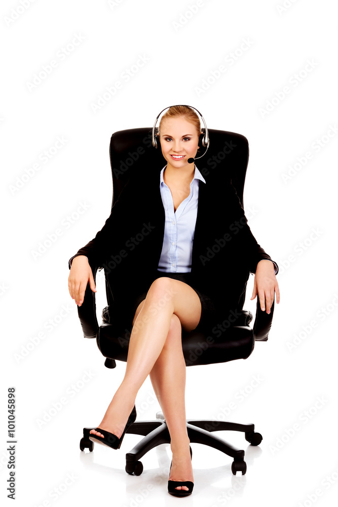 Smiling phone operator in headphones sitting on armchair Smiling phone operator in headphones sitting on armchair