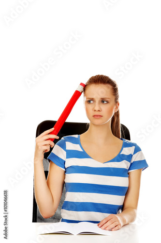 Teenage woman doing homework and holding huge pen
