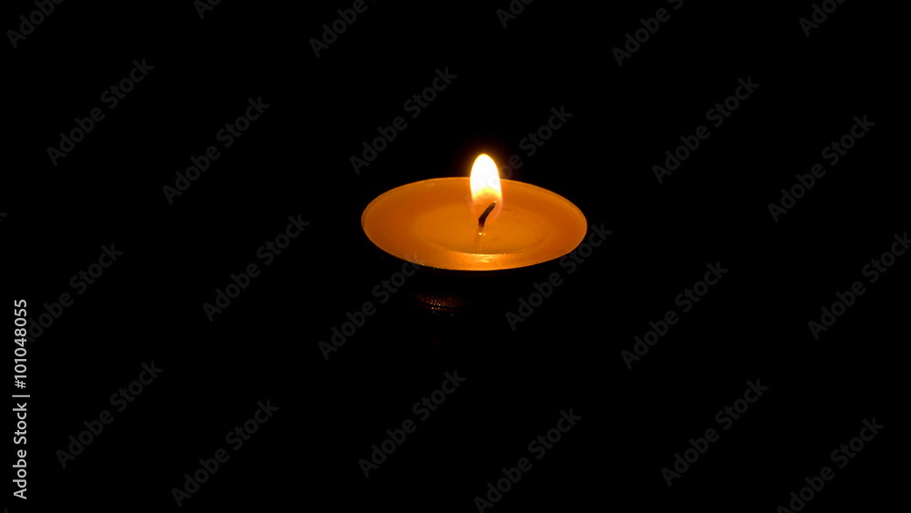 A small candle floating on water in the dark A small candle floating on water in the dark
