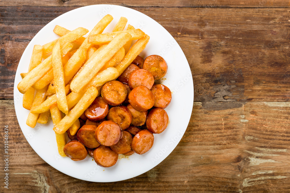 currywurst mit pommes auf einen holzuntergrund currywurst mit pommes auf einen holzuntergrund