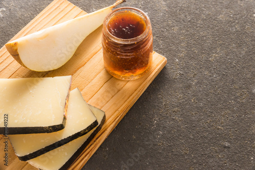 Some sliced typical Pecorino cheese with a sliced pear and a little jam jar