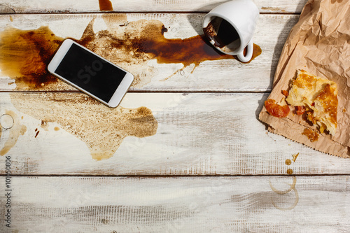 Cup of coffee spilled on wooden table photo