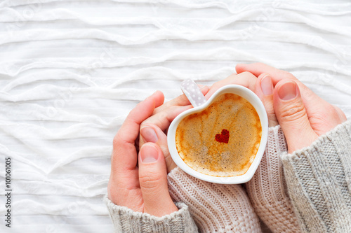 Woman and man holds a cup of hot coffee with cinnamon heart. Valentine's Day background.