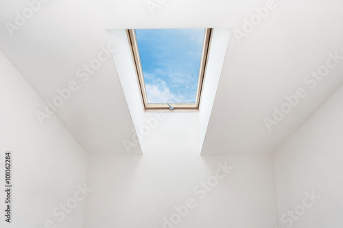 A modern open skylight  mansard window  in an attic room against blue sky