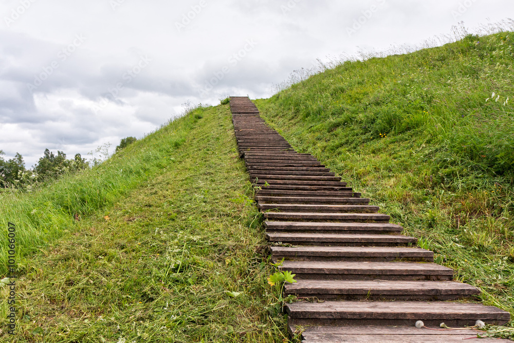 Long wood stairs to top of grass-covered earth-deposit. Belozersk, Vologodsky region, Russia. 
