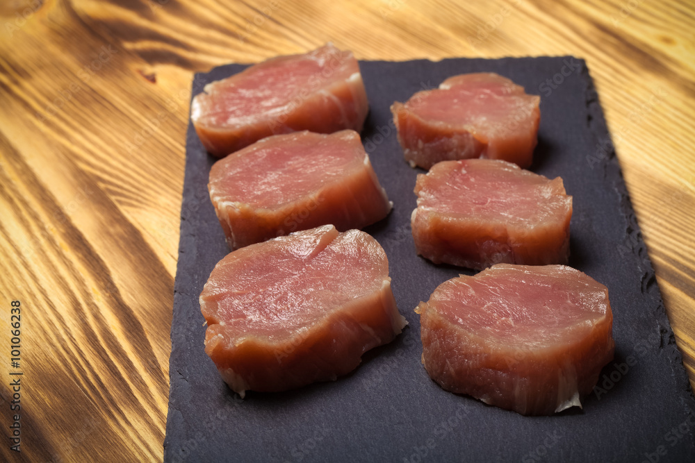 Pieces of raw meat on a plate of slate on a new burned wooden ba Pieces of raw meat on a plate of slate on a new burned wooden ba