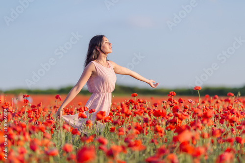 Young woman in poppy field in evening time