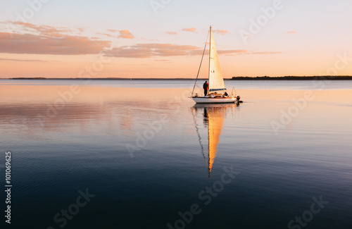 Sailing boat on a calm lake with reflection in the water Fototapet