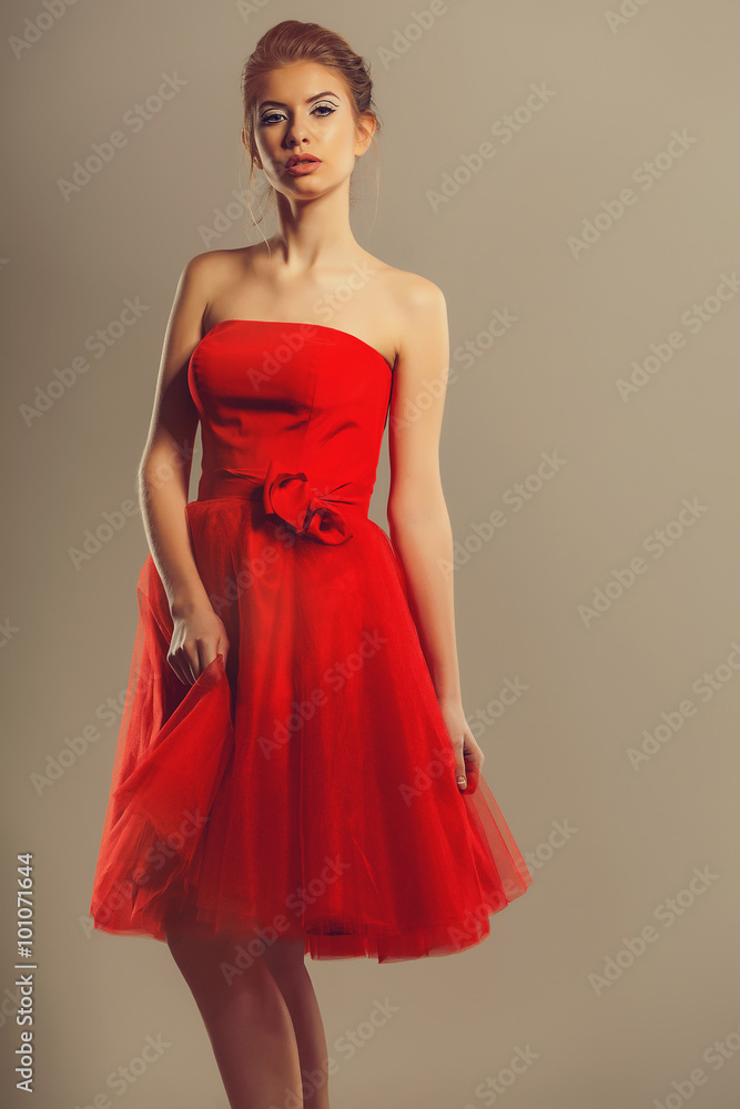 Confident model in a red flowing dress in studio Confident model in a red flowing dress in studio