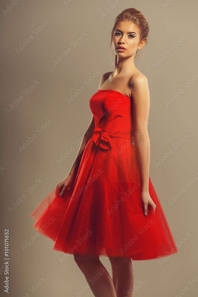 Confident model in a red flowing dress in studio Confident model in a red flowing dress in studio