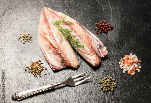 raw fresh mackerel fillet with silver fork andl spices over slat