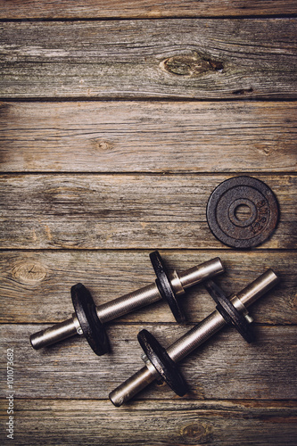 Old iron dumbbells with extra plates on an old wooden table. Image taken from above, top view. 