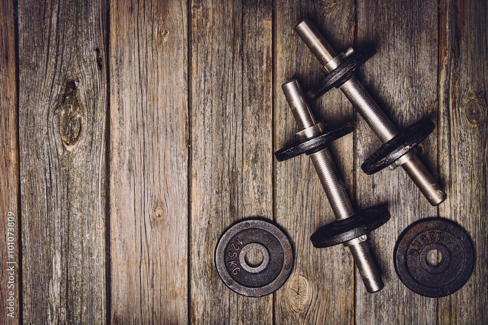 Old iron dumbbells with extra plates on an old wooden table. Image taken from above, top view. Old iron dumbbells with extra plates on an old wooden table. Image taken from above, top view.