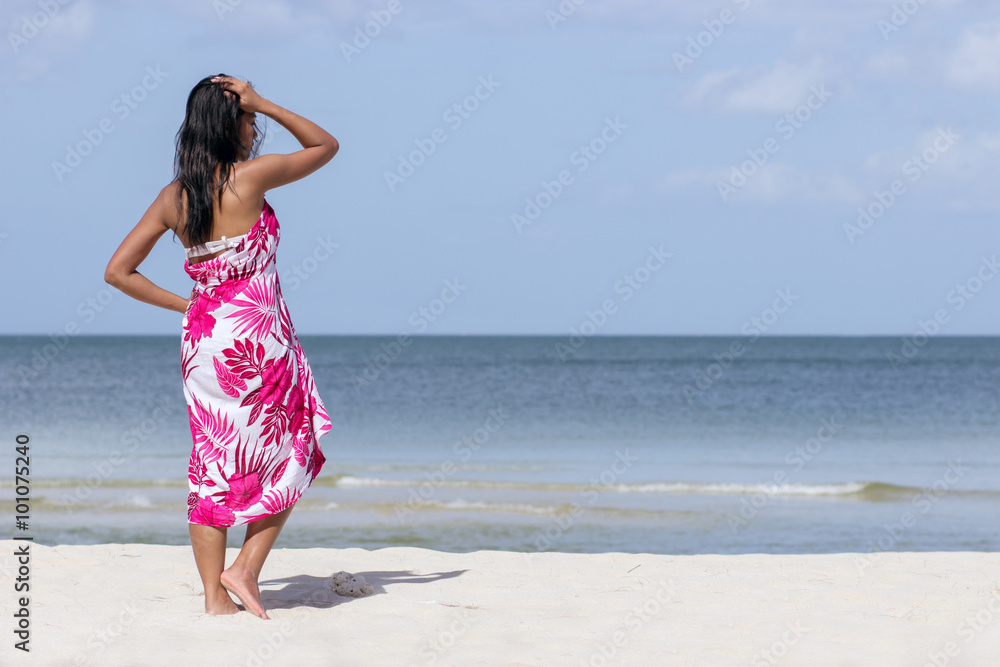 woman in a dress standing on the beach looking out to sea woman in a dress standing on the beach looking out to sea