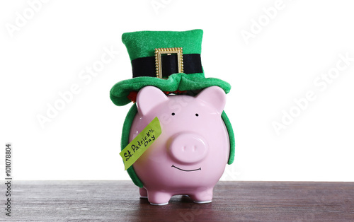 Piggy bank with St. Patrick hat wooden table, on white background