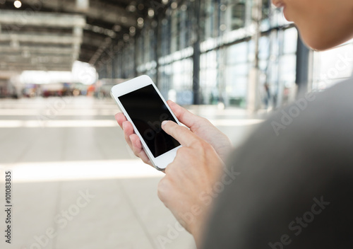 Woman in a airport terminal connecting with her smartphone. 