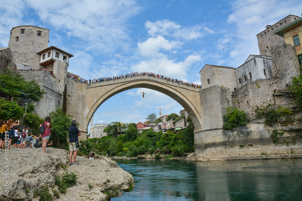 Man jumping from a very high ancient bridge in Mostar.