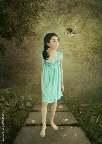 Little girl smiling in a blue nightgown is walking in the garden in the early morning photo