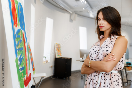Young caucasian woman standing in art gallery front of paintings