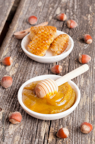 Honey with wooden honey dipper and ceramic bowl honeycomb
