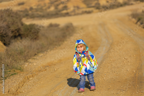 cute little girl with backpack travel on the road