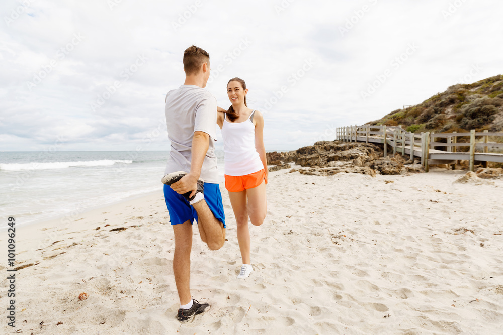 Runners. Young couple exercising and stertching on beach Runners. Young couple exercising and stertching on beach