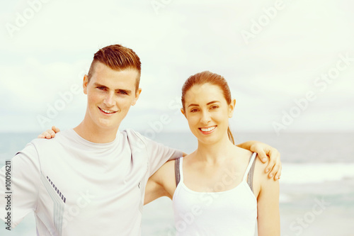 Young couple looking at camera standing on beach