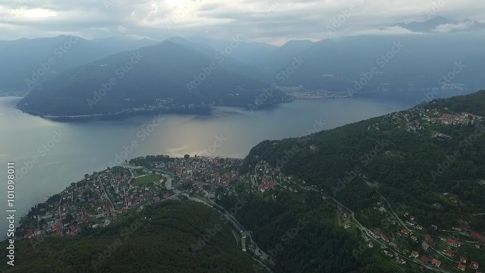 Aerial shot of big lake with mountains and village at sunset Aerial shot of big lake with mountains and village at sunset