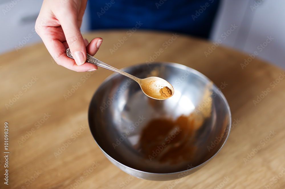 The cook has small spoon of cinnamon in hand The cook has small spoon of cinnamon in hand