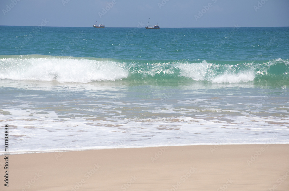 Boats sailing in the clear blue waters of the Indian Ocean on a bright sunny day in Sri Lanka