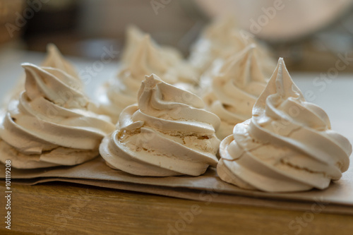 Creamy meringues on a parchment stays in a line