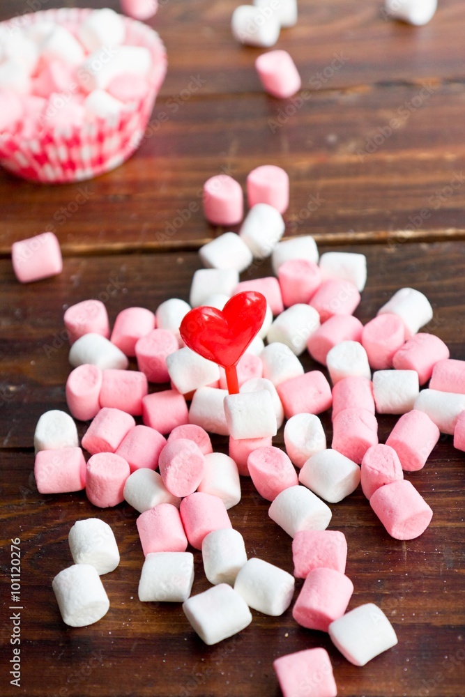 Marshmallows with hearts on wooden background