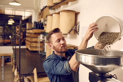 Foto Entrepreneur pouring raw coffee beans into a modern roasting mac